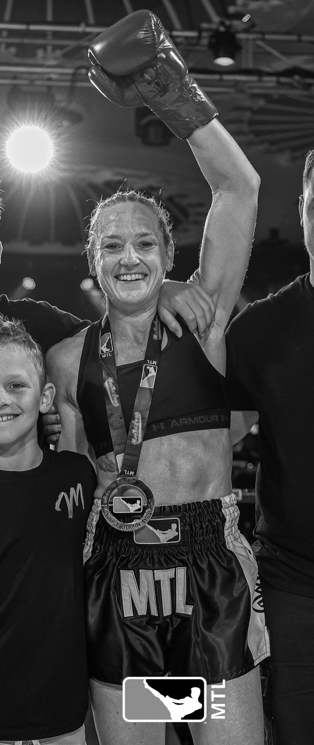 Mardi Davies with her glove raised after a Muay Thai win